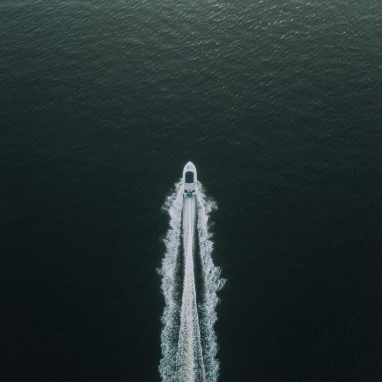 Aerial view of a motorboat speeding through the open sea, leaving a white wake behind