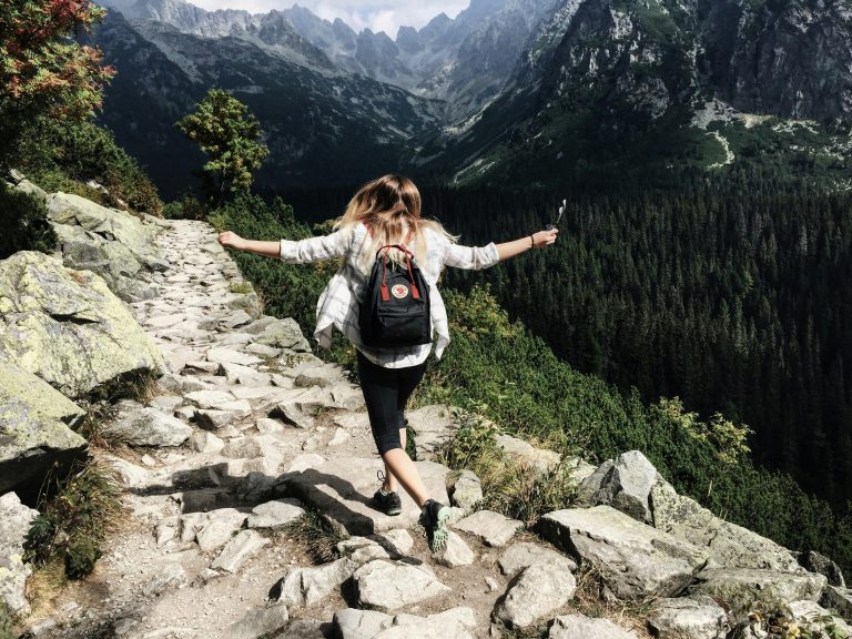 Woman hiking on rocky mountain trail with breathtaking valley view