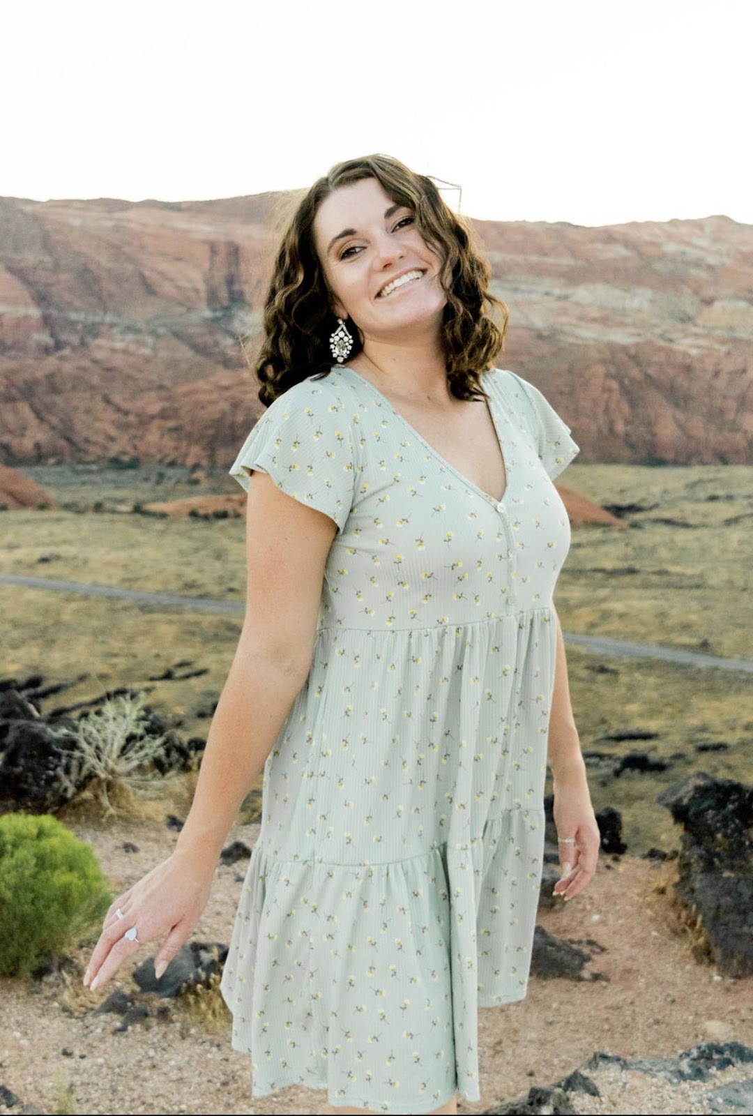 Smiling woman in floral dress standing in front of rocky desert landscape