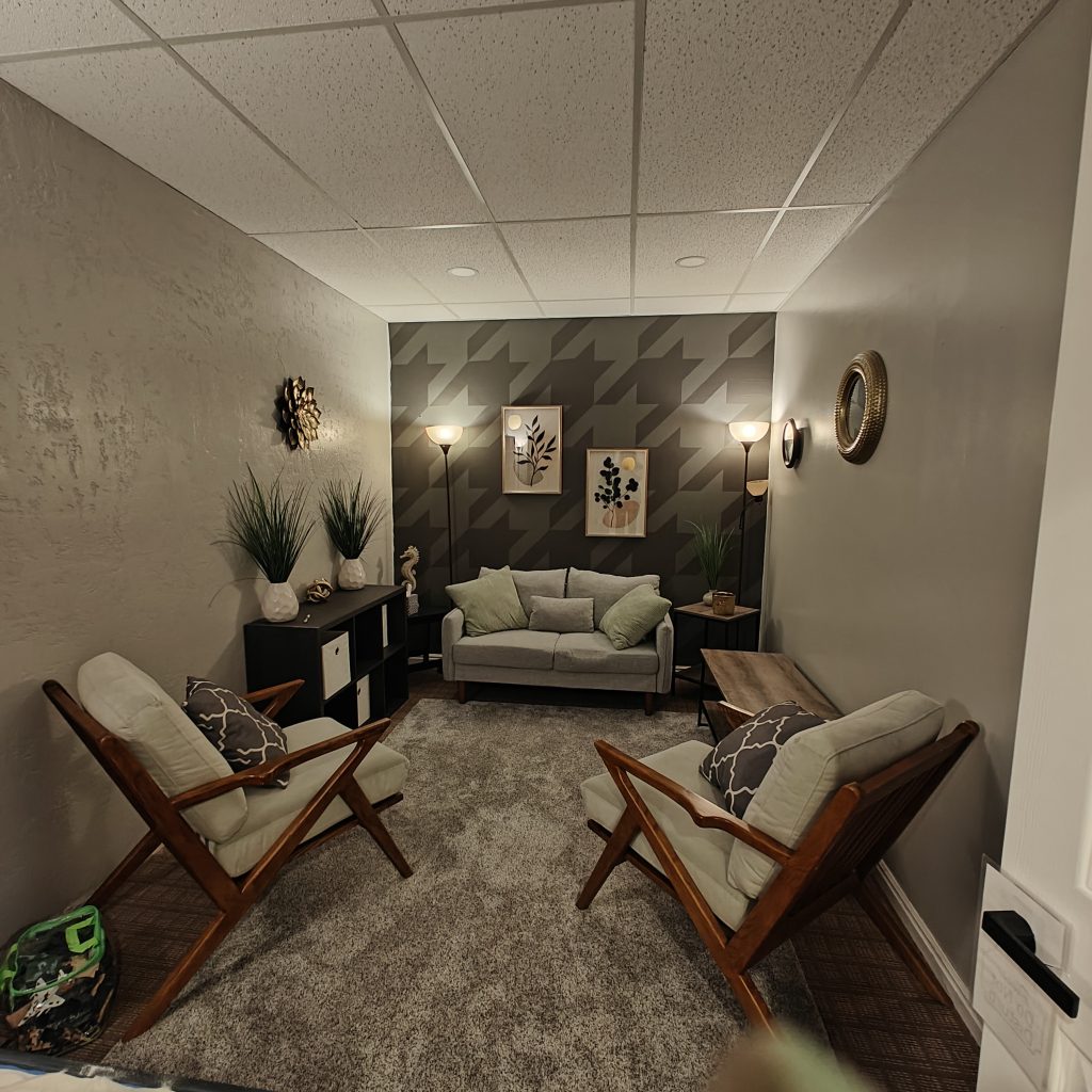 Cozy living room with armchairs, sofa, plants, and wall art in modern decor, herringbone accent wall, soft lighting